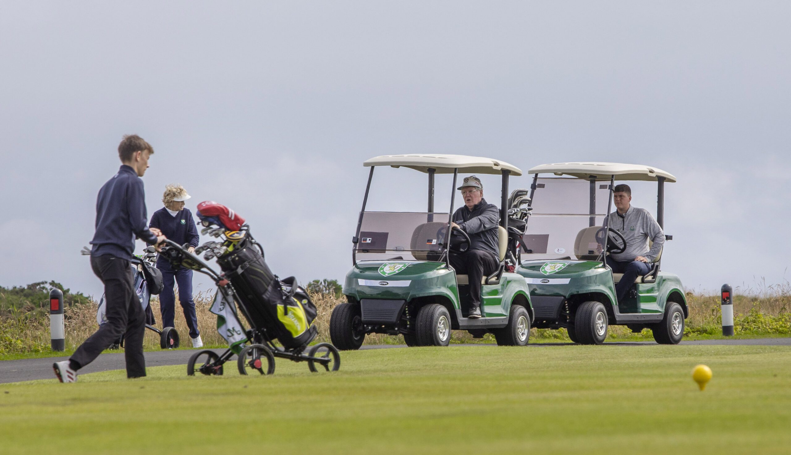 Golfers riding STAR EV Capella 2 Pro machines at Royal Dornoch Golf Club.