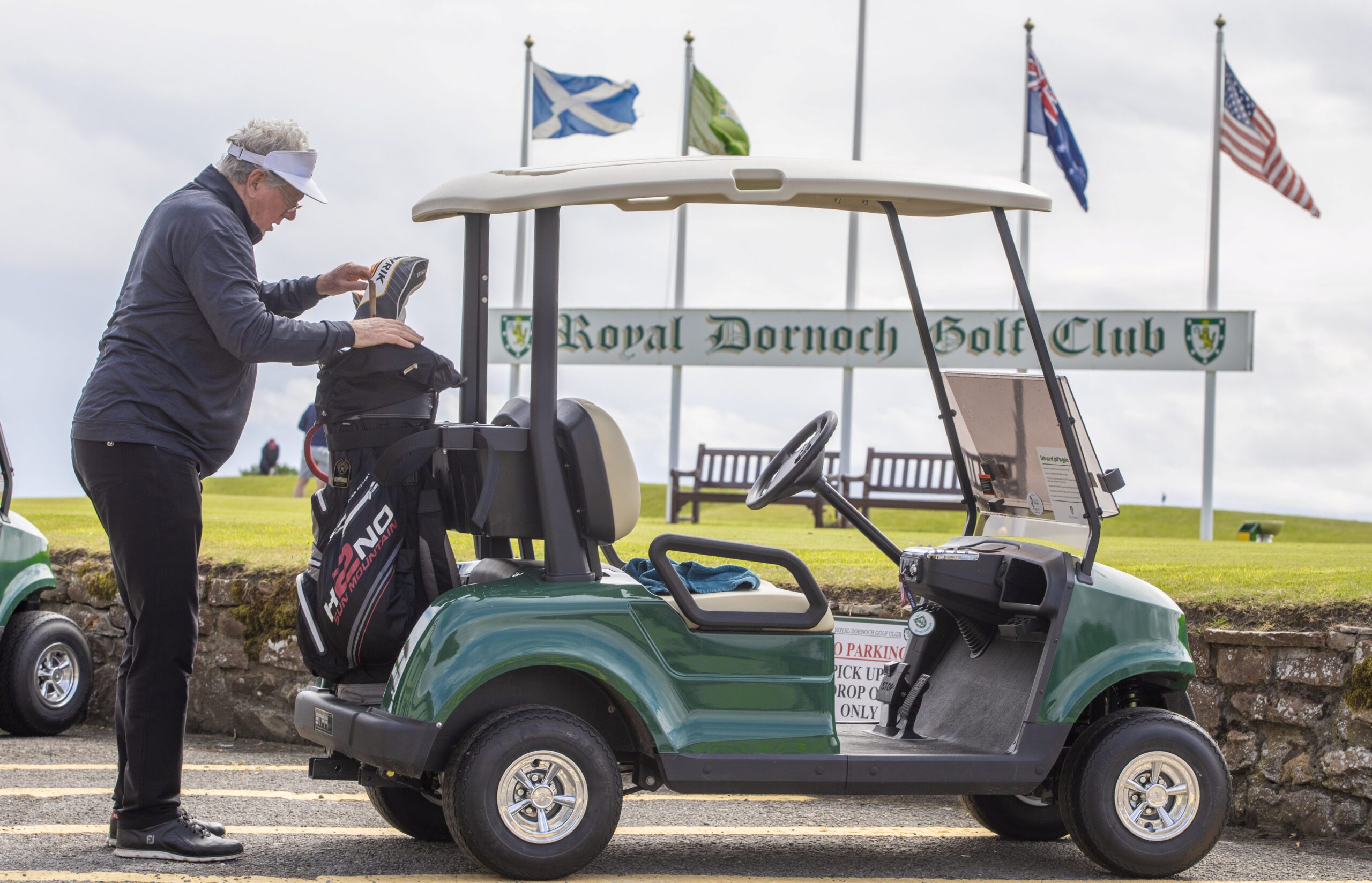 Golfer accessing his bag on the back of a STAR EV Capella 2 Pro at Royal Dornoch Golf Club.