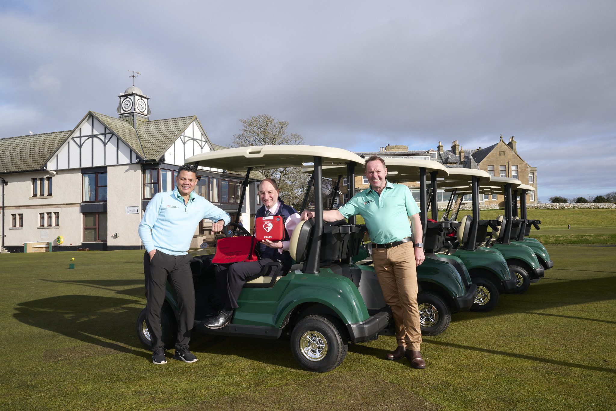 A man holding a defibrillator sitting on Royal Dornoch Golf Club's STAR EV Capella.